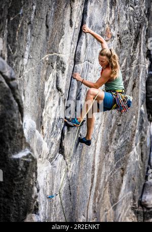 Giovane donna bionda sale in testa in una parete di granito sovrastante, Maltatal, Carinzia, Austria Foto Stock