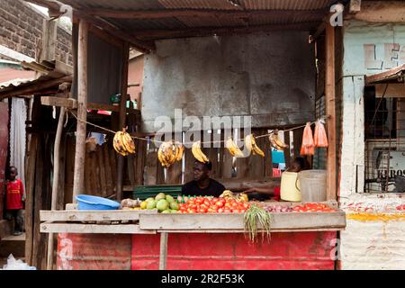 Kenyans alla sua bancarella di frutta e verdura nella baraccopoli, Eastleigh, Nairobi, Kenya Foto Stock