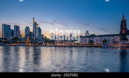 Vista dell'Eiserner Steg, del quartiere bancario e del Kaiserdom poco dopo il tramonto a Francoforte, in Germania Foto Stock