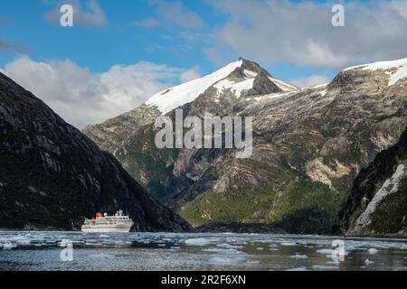 Mentre i passeggeri si godono il viaggio con un gommone Zodiac lungo il ghiacciaio, la nave da crociera della spedizione MS Bremen (Hapag-Lloyd Cruises) è surro Foto Stock