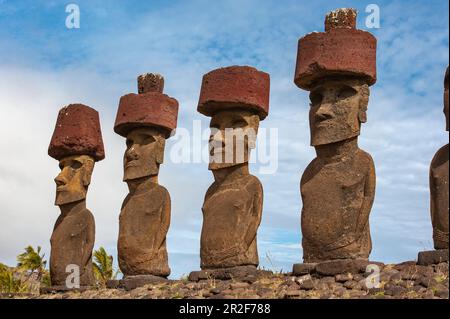 Una persona in primo piano è offuscata da un gruppo di Moais in piedi su una pietra cerimoniale o AHU dal 1250 al 1500, Rapa Nui, Isola di Pasqua, Cile Foto Stock