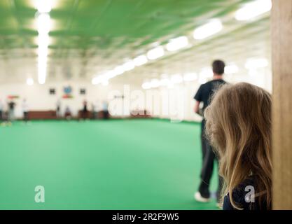 Una giovane ragazza guarda giocare al bowling al prato al coperto Ayr Green in Scozia Foto Stock