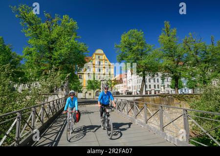 Uomo e donna cavalcano una bicicletta sul ponte per il nuovo castello di Ingolstadt, Ingolstadt, il percorso ciclabile del Danubio, l'alta Baviera, Baviera, Germania Foto Stock