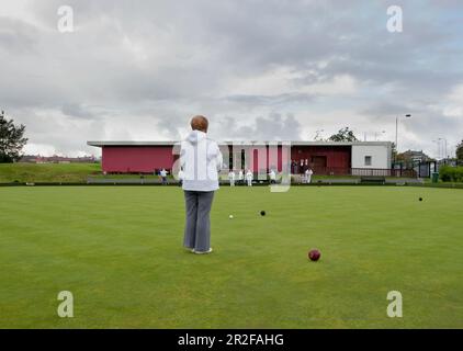 Bocce in gioco di fronte al circolo del padiglione rosso presso il campo da bowling Balornock a Glasgow, Scozia, Regno Unito Foto Stock