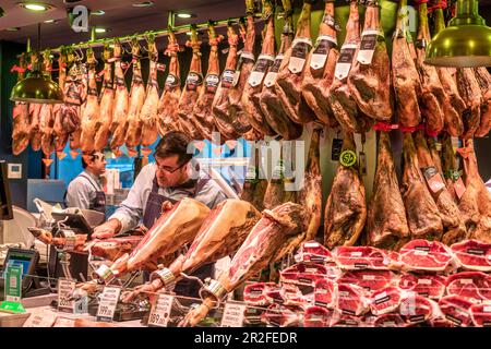 Mercat de la Boqueria, uomo taglio jamon serrano, stand prosciutto, mercato al coperto, Barcellona, Spagna Foto Stock