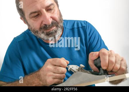 Vista frontale di un falegname maschio bearded piantare legno con una piantatrice manuale isolato su sfondo bianco Foto Stock