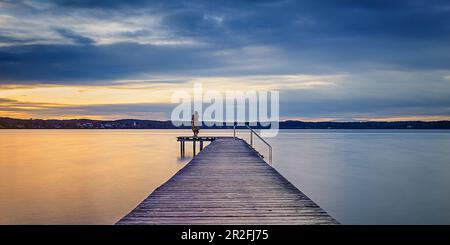 Donna sul molo al tramonto sul Lago Starnberg, St. Heinrich, Baviera, Germania Foto Stock