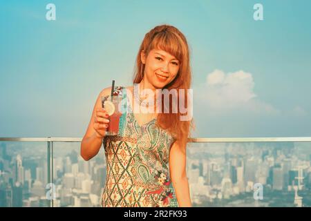 Donna con un bicchiere di cocktail, mocktail e bevande rinfrescanti al bar sul tetto Foto Stock