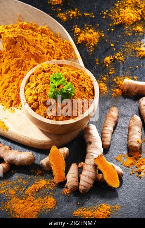 Composizione con una ciotola di curcuma macinato e il suo rizoma fresco Foto Stock