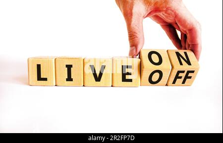 Simbolo Live on o Off. L'uomo d'affari gira i cubi di legno e cambia la parola Live Off in Live on. Bellissimo sfondo bianco tavolo. Business e live Foto Stock