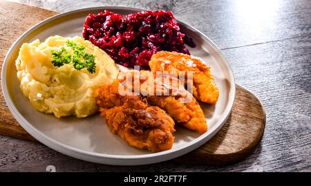 Cotolette di pollo impanate servite con patate e barbabietole Foto Stock