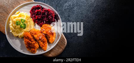 Cotolette di pollo impanate servite con patate e barbabietole Foto Stock