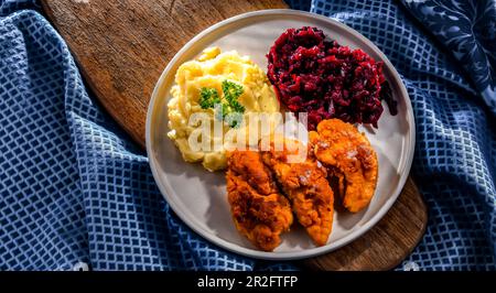 Cotolette di pollo impanate servite con patate e barbabietole Foto Stock