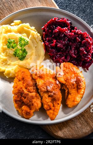 Cotolette di pollo impanate servite con patate e barbabietole Foto Stock