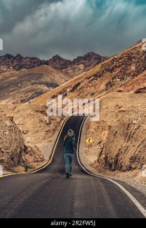 Donna che corre su strada nella Valle della morte, Parco Nazionale della Valle della morte; Nevada, California, Stati Uniti, Nord America Foto Stock