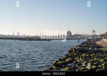 Vista dal molo occidentale al porto di Warnemünde al mattino. Il cantiere navale di Warnemünde è all'orizzonte. Foto Stock