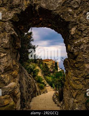 Vista attraverso un arco di pietra nel Jardin Exotique di Èze sulle vecchie case del villaggio, Èze, Costa Azzurra, Francia Foto Stock