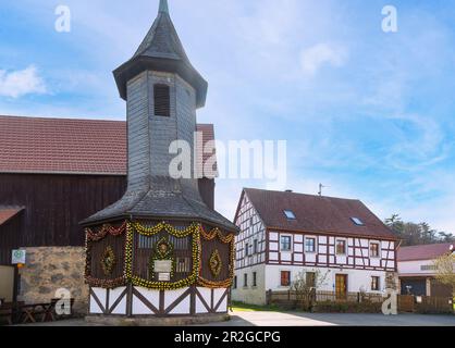 Fontana casa decorata con colorate uova di Pasqua con presepe pasquale a Birkenreuth in Franconia Svizzera, Baviera, Germania Foto Stock