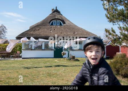 Lavanderia flapping nel vento, casa di paglia, ragazzo con casco da bicicletta, Neuendorf, Hiddensee Island, Meclemburgo-Pomerania occidentale, Germania Foto Stock