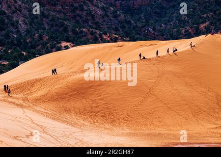 I visitatori che si arrampicano e calano sul Coral Pink Sand Dunes state Park, Utah, USA Foto Stock