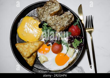 Una deliziosa colazione a base di uova, pomodori, verdure, pane e bistecca in un hotel di lusso Foto Stock