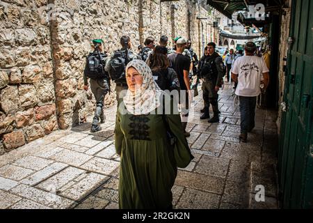 Gerusalemme, Israele. 18th maggio, 2023. Una donna palestinese passa davanti agli ufficiali della polizia di frontiera israeliana che marciano nella vecchia città murata di Gerusalemme durante la marcia della bandiera. Decine di migliaia di giovani uomini e donne religiosi-sionisti hanno marciato attraverso la capitale sventolando le bandiere Star of David nella Città Vecchia di Gerusalemme, come parte di una controversa marcia della bandiera, Segnando la riunificazione della città durante la guerra dei sei giorni e la cattura da parte di Israele del Monte del Tempio e del Muro Occidentale, i siti più sacri dell'Ebraismo. Credit: SOPA Images Limited/Alamy Live News Foto Stock