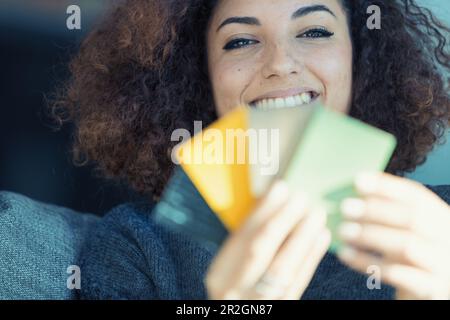 Una donna dai capelli ricci sceglie gioiosamente i colori dai campioni per la mobilia o la pavimentazione nel paese. È profondamente investita nella personalizzazione del suo stile di vita con h Foto Stock