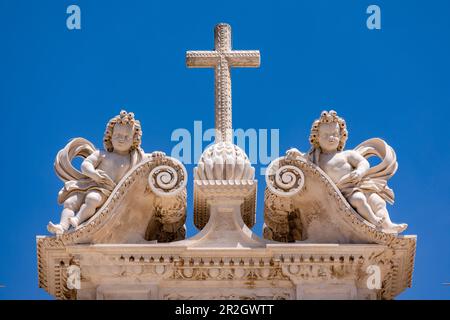 La croce con due angeli in cima alla reale Abbazia di Alcobaca con un cielo blu, Portogallo Foto Stock