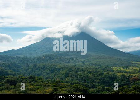 Un lussureggiante giardino in La Fortuna, Costa Rica con il Vulcano Arenal in background Foto Stock