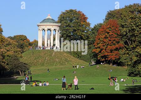 La gente può trascorrere un pomeriggio autunnale nel Giardino Inglese, con i Monotteri sullo sfondo, Monaco, alta Baviera, Baviera, Germania Foto Stock