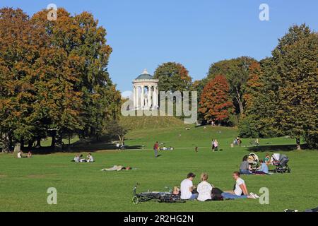 La gente può trascorrere un pomeriggio autunnale nel Giardino Inglese, con i Monotteri sullo sfondo, Monaco, alta Baviera, Baviera, Germania Foto Stock