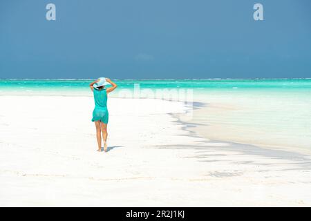 Donna che cammina su idilliaca spiaggia vuota, Zanzibar, Tanzania, Africa orientale, Africa Foto Stock