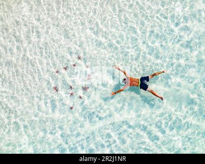 Vista aerea del turista ammirando il colorato snorkeling stelle marine nella laguna turchese, Zanzibar, Tanzania, Africa orientale, Africa Foto Stock