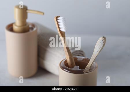 Supporto di spazzolini da denti e accessori da bagno in bambù su tavolo bianco Foto Stock