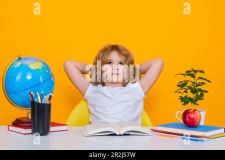 Allievo nerd della scuola elementare con libro isolato su sfondo giallo studio. Intelligenza geniale intelligente capretto pronto per imparare. Ritorno a scuola. Foto Stock