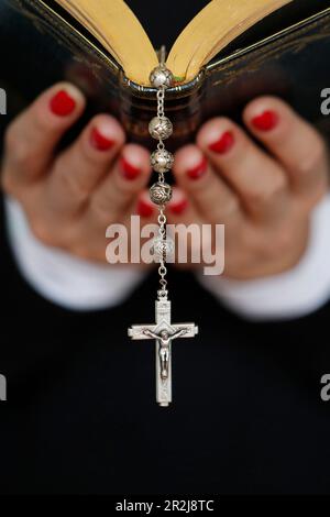 Donna che legge la Bibbia, primo piano sul rosario vintage con crocifisso, fede e religione, Francia, Europa Foto Stock