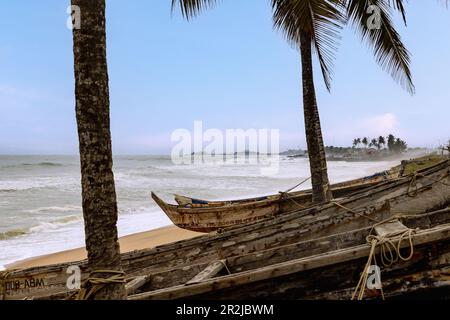 Spiaggia di Elmina con piroghe e vista del Castello di Elmina sulla Gold Coast nella regione centrale del Ghana meridionale in Africa occidentale Foto Stock