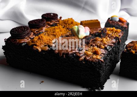 Pezzi di brownie fresco su sfondo bianco. Torta al cioccolato deliziosa e dolce Foto Stock