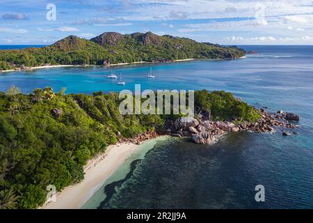 Veduta aerea di Anse St. Spiaggia Jose con barche a vela nella baia di Baie Laraie in lontananza, isola di Curieuse, Seychelles, Oceano Indiano Foto Stock