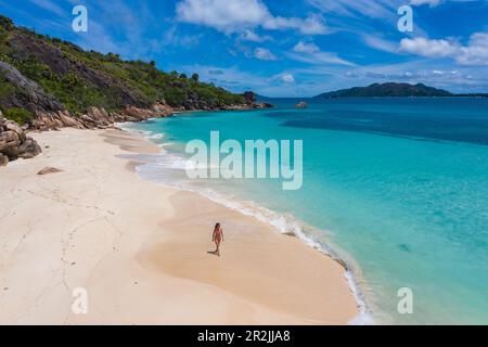 Veduta aerea di una giovane donna che cammina sulla spiaggia di Anse St Jose, sull'isola di Curieuse, sulle Seychelles, sull'Oceano Indiano Foto Stock