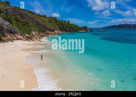 Veduta aerea di una giovane donna che cammina sulla spiaggia di Anse St Jose, sull'isola di Curieuse, sulle Seychelles, sull'Oceano Indiano Foto Stock