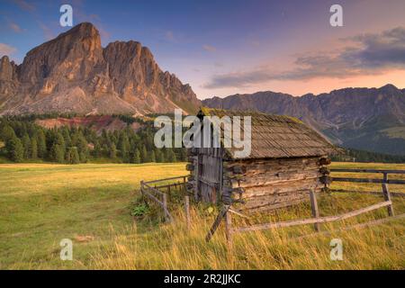 Piccola capanna di legno al tramonto di fronte al Peitlerkofel, Alto Adige, Italia. Foto Stock