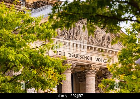 L'iscrizione DEM Deutschen Volke sull'architrave nel portale ovest dell'edificio del Reichstag visto tra alberi, Berlino, Germania Foto Stock