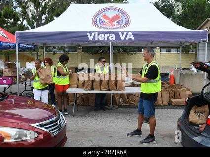 Orlando, Stati Uniti. 19th maggio, 2023. I volontari aspettano di mettere gli articoli alimentari in veicoli in un evento di distribuzione alimentare militare e veterano per coloro che ne hanno bisogno, sponsorizzato da Lockheed Martin e dagli angeli nazionali no profit Soldiersí presso la clinica del Lago Baldwin VA a Orlando. In riconoscimento del mese dell'apprezzamento militare, 200 veterani preregistrati dell'area di Orlando, militari attivi, guardiani e riservisti hanno ricevuto in media 75 libbre di frutta e verdura fresca, carni e non-deperibili all'evento. Credit: SOPA Images Limited/Alamy Live News Foto Stock