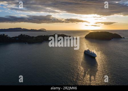 Veduta aerea della nave da crociera della spedizione World Voyager (crociere nicko) in silhouette al tramonto con promontorio e isola oltre, Playa Flamingo, Guanacast Foto Stock