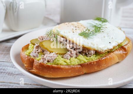 Toast all'avocado con tonno, uova fritte e aneto sul piatto. Foto Stock