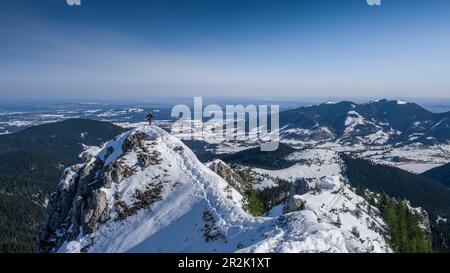 L'uomo si trova sulla cima di Teufelstaettkopf in sci tour in inverno e si affaccia sulla valle innevata delle Alpi Ammergau in Baviera in inverno Foto Stock