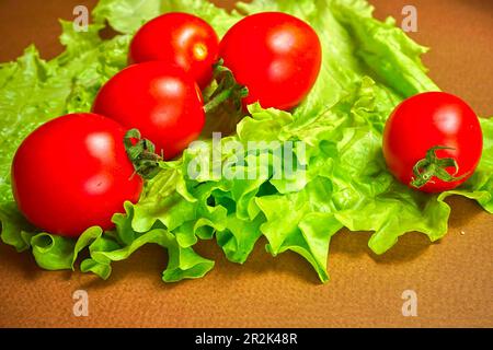 I pomodori ciliegini rossi si trovano su una foglia di lattuga Foto Stock