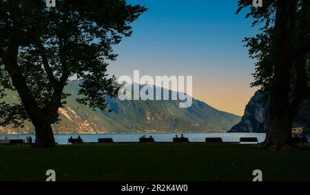 Persone in attesa del tramonto sulla riva del Lago di Garda, a Riva del Garda. Trento. Italia Foto Stock