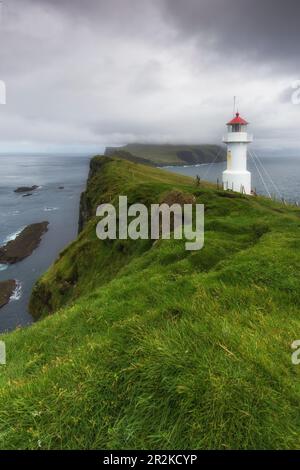 Vista delle scogliere e del faro di Mykines Holmur fino a Mykines, Isole Faeroe. Nuvole scure. Foto Stock